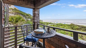 A balcony with a table, chairs, and a view of the beach.