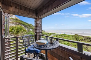 Un balcón con mesa, sillas y vista a la playa.