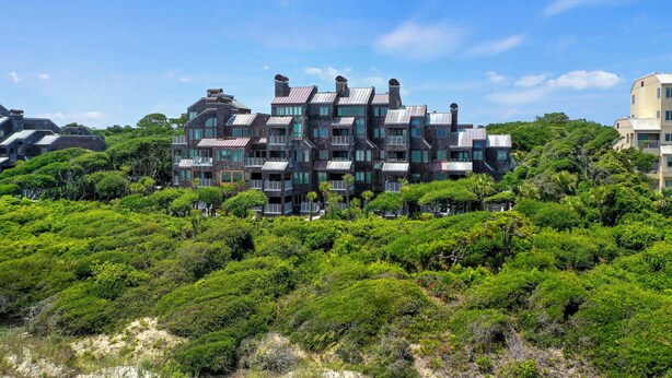 A modern multi-story building with a unique architectural design, surrounded by lush greenery.