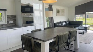 Cocina moderna con electrodomésticos integrados, comedor con mesa y sillas, y vistas al exterior.