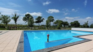 Una piscina rectangular con interior azul, rodeada por un deck con baldosas.