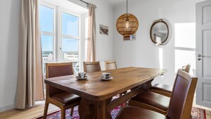 A dining area with a wooden table, six chairs, a hanging light fixture, a mirror, and a window with curtains. - 3 bedroom pet friendly home in Ribe (Ribe)