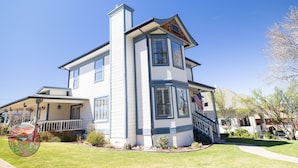 A two-story house with a covered porch, a chimney, and a flag.