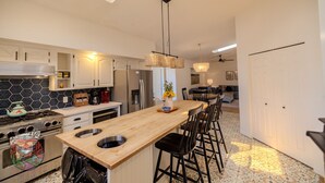 A modern kitchen with a central island, stainless steel appliances, and a dining area with a chandelier.