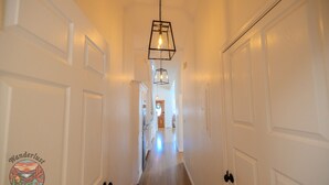 A hallway with white doors, a hanging light fixture, and a logo on the wall.