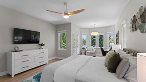 Une chambre à coucher comprenant un lit, une commode, un téléviseur et un ventilateur de plafond.