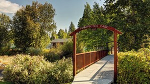 Een houten bogenpoort met de tekst 'Prospector Park', leidend naar een verharde looppad omringd door groen.