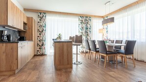 A modern kitchen with wooden cabinets and a dining area with a table and chairs. - Attractive Chalet With Sauna (Sankt Lambrecht)