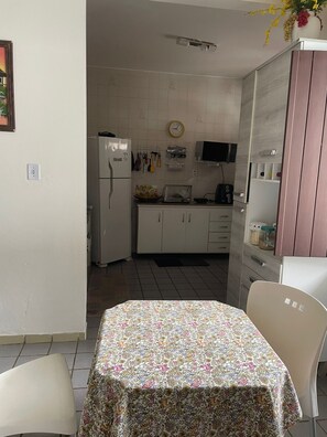 A compact kitchen with a refrigerator, microwave, and a clock on the wall. - Quarto com 2 camas de solteiros (Vera Cruz)