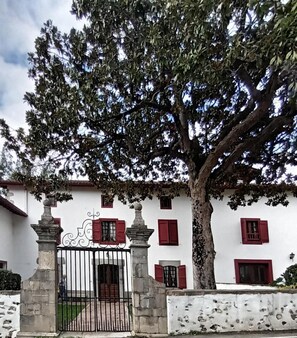 Traditional building with a gated entrance and a large tree providing shade.