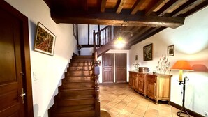 Eine Treppe führt zu einer zweiten Etage, Holzschränke, eine Lampe und ein gefliester Boden sind zu sehen.