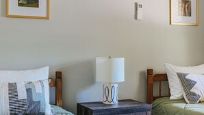 Une chambre avec deux lits, une table de chevet, une lampe et un appareil de climatisation.