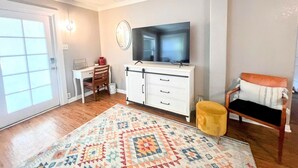 A living room with a television, a desk, a chair, a sofa, and a patterned rug.