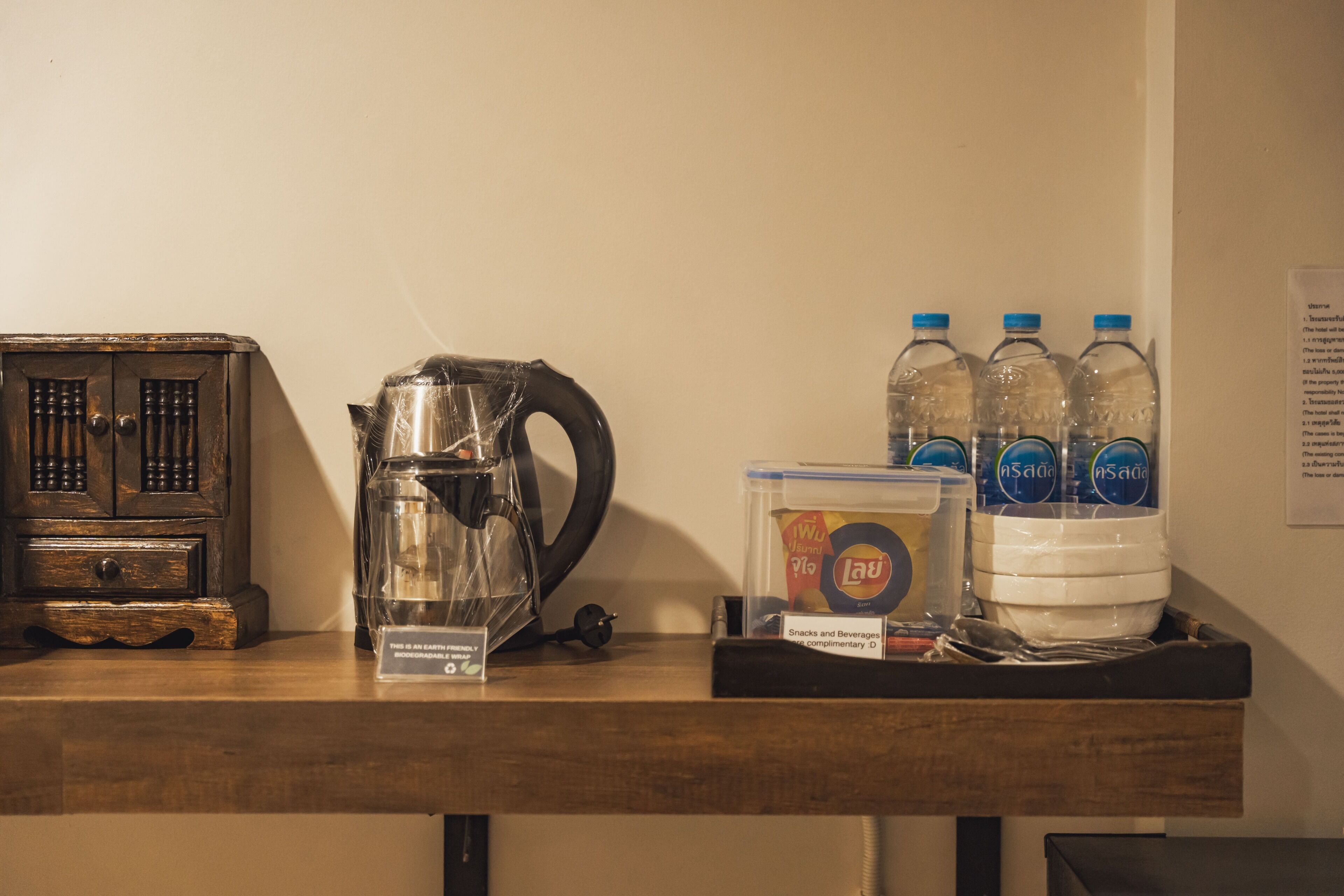 A wooden table with a vintage radio, a glass carafe, and bottled water.