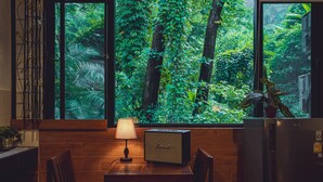 A kitchen with a wooden table, chairs, a radio, and a refrigerator. - Namtok Sarika Resotel (Nakhon Nayok)