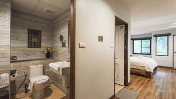 Un baño moderno con diseño de pared de madera, inodoro, lavamanos y zona de ducha.