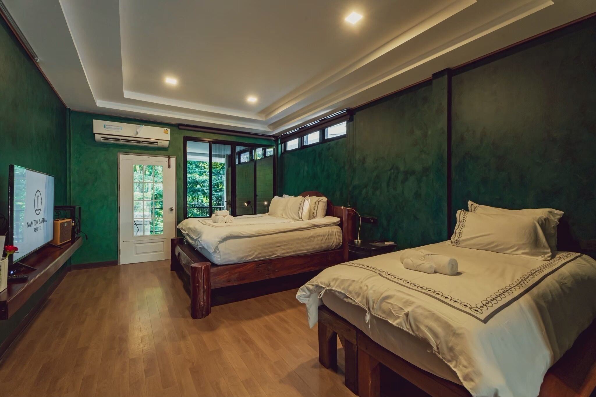 A room with two beds, a television, and an air conditioning unit.