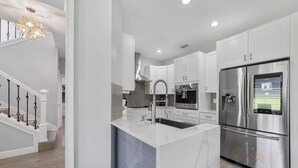 A modern kitchen with white cabinetry, stainless steel appliances, and a marble island.