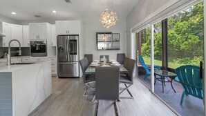 A modern kitchen with white cabinets, stainless steel appliances, and a dining area with a glass table and chairs.