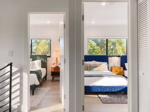 Een hotelkamer met een bed, nachtkastjes, een lamp en uitzicht op groen.