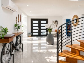 Ein modernes Interieur mit Treppe, Essbereich und einer großen Tür.