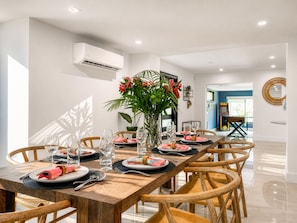 A dining area with a long wooden table set for a meal, surrounded by wicker chairs. - Villa Palma: Heart of Miami | 5 min to Miracle Mile (Miami)
