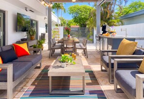 A modern outdoor living space with a sofa, chairs, a dining table, and a grill area. - Villa Palma: Heart of Miami | 5 min to Miracle Mile (Miami)