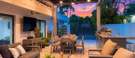 An outdoor patio with a dining area, seating, and a kitchen.