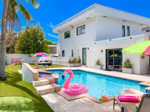 A modern house with a swimming pool, a pink flamingo float, and a children's play area. - Villa Palma: Heart of Miami | 5 min to Miracle Mile (Miami)