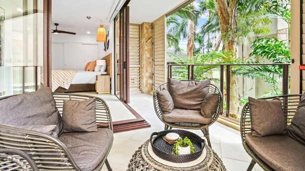 Una habitación con muebles de mimbre, una cama y vista a espacios verdes.