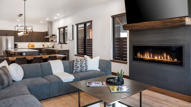 A modern living room with a sectional sofa, a coffee table, and a fireplace.