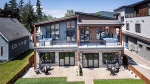 A two-story house with a patio area featuring outdoor seating and a barbecue grill.