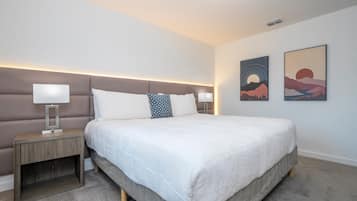 Quarto moderno com uma cama grande, uma mesa de cabeceira e duas obras de arte penduradas na parede.
