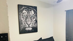 Ein Schlafzimmer mit einem Bett, einem Deckenventilator, einer Wandleuchte und einem gerahmten Bild.