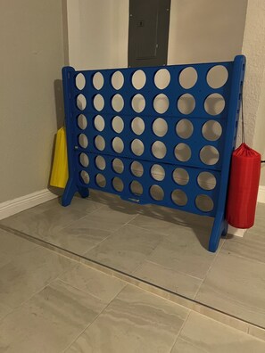A blue pegboard with multiple holes, a yellow bag, and a red bag against a wall with a door.
