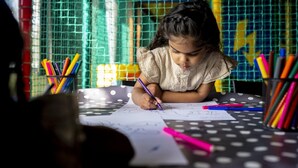A child writing at a table with colorful pens and pencils, surrounded by a wire mesh and a yellow wall. - Cozy Glamping in Mierlo (Mierlo)