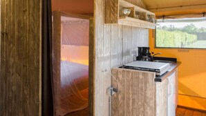 A compact kitchen with a built-in stove, a coffee maker, and a window overlooking a garden. - Cozy Glamping in Mierlo (Mierlo)