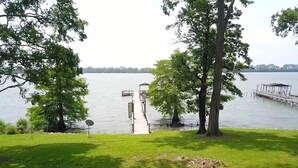 A grassy area with a dock extending into a calm lake, surrounded by trees. - Eagle Lake Escape - lakefront - private lot (Vicksburg)