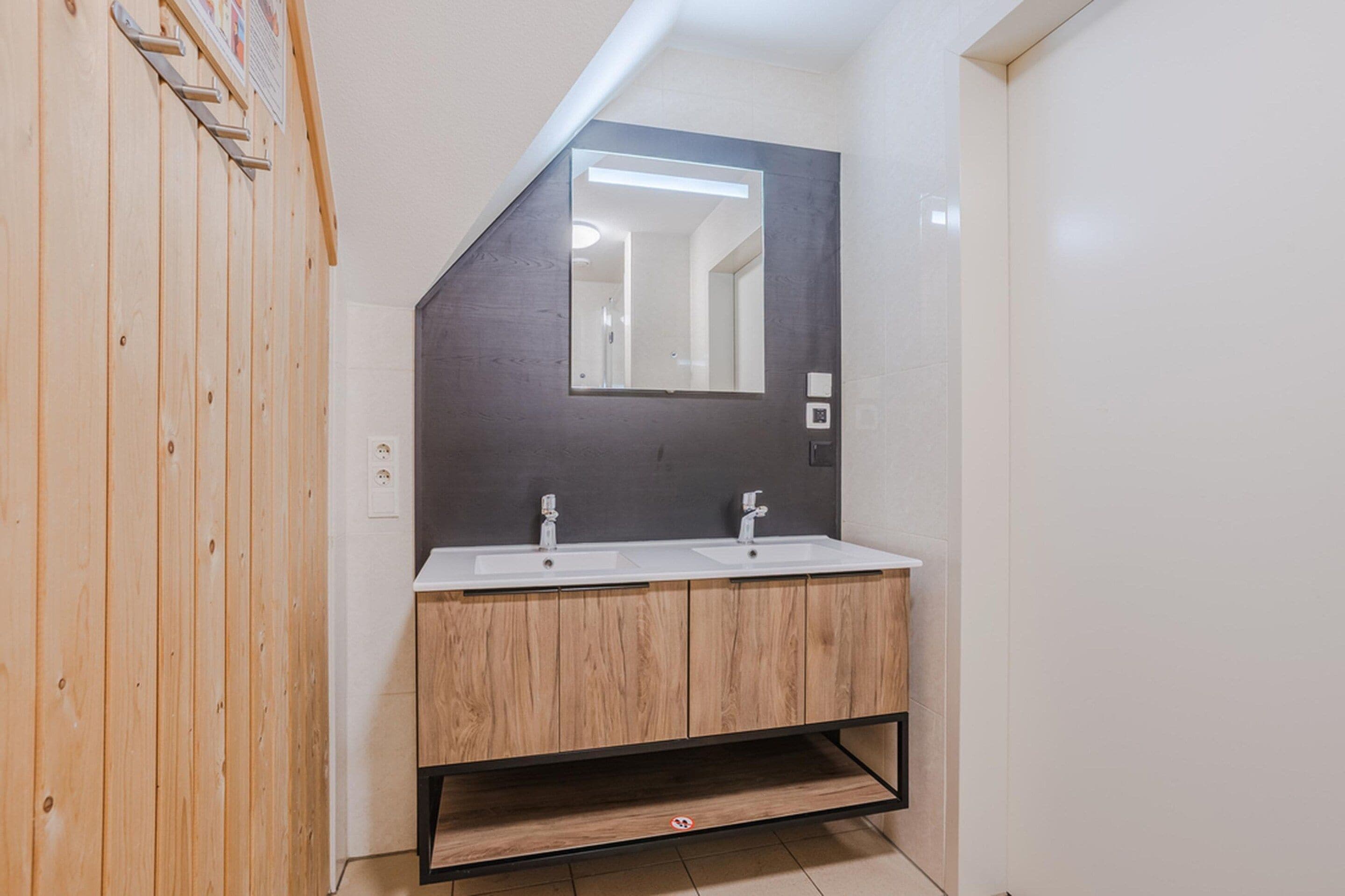 A modern bathroom with a wooden vanity, two sinks, and a large mirror.