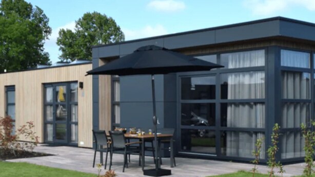A modern building with a patio area featuring a table and chairs under a large umbrella. - Sustainable Holiday Home on the Ijsselmeer (Enkhuizen)