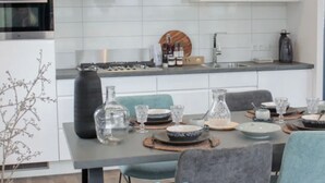 A modern kitchen with white cabinets, a stainless steel oven, a gas stove, and a hanging copper pendant light. - Sustainable Holiday Home on the Ijsselmeer (Enkhuizen)