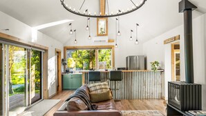 Un salón moderno con sofá, chimenea y una cocina visible a través de una puerta de cristal.