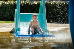 A child sitting on a blue slide in a water park. - Cottage in Zeeland With Pet-friendly Stay (Koudekerke)