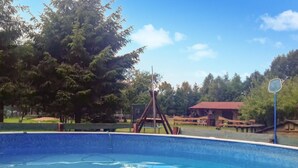 A swimming pool with a wooden swing set and a basketball hoop in a park-like setting. - 1 bedroom pet friendly home in Rekowo (Rekowo)