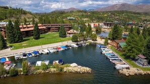 A lakeside hotel with a marina, surrounded by mountains and dense forest. - Lakefront Condo, Ground Floor - Fireplace + Two Patios - Ideal for Couples or Families (Grand Lake)