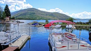 A lake with boats docked at a pier, surrounded by mountains and trees. - Lakefront Condo, Ground Floor - Fireplace + Two Patios - Ideal for Couples or Families (Grand Lake)