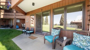 A covered outdoor area with wicker furniture, a patio table, and a flag. - Lakefront Condo, Ground Floor - Fireplace + Two Patios - Ideal for Couples or Families (Grand Lake)