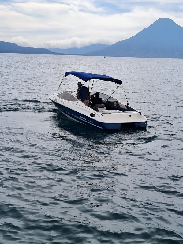 A small motorboat on calm water with a mountainous backdrop.