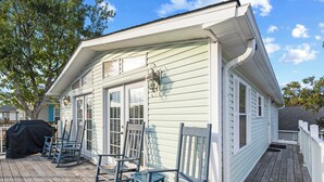 Une maison avec un porche, un barbecue couvert et un espace salon extérieur.