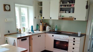 Een keuken met witte kastjes, een fornuis, een vaatwasser en een raam.